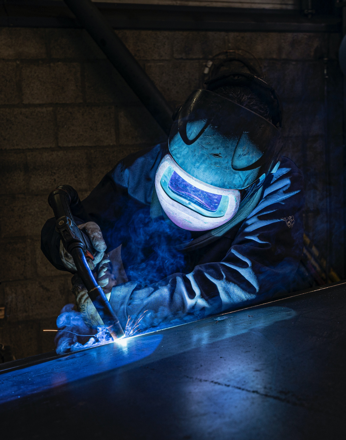 person i svejsedragt der svejser en overflade